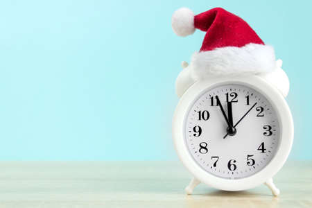 White alarm clock with red santa cup on wood table with blue backgroundの写真素材