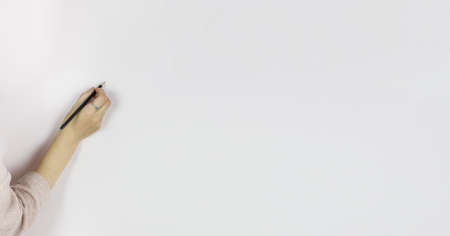 Female hand holding pencil on white background, Writes in pencil on a gray wall, Copy spaceの写真素材