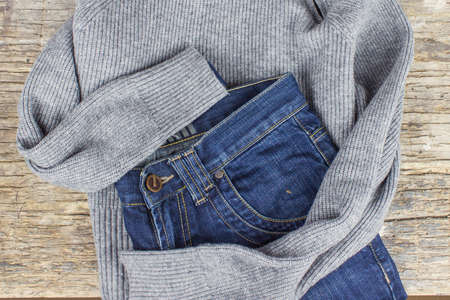 Top view of blue jeans and gray sweater on wooden background. Fashion clothing conceptの写真素材