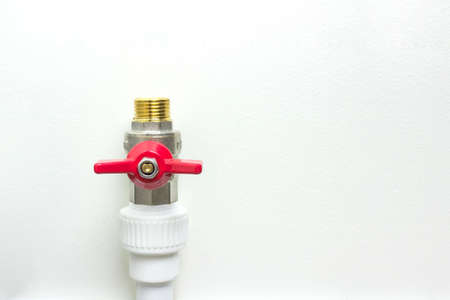 White polypropylene pipe and red faucet. Fittings for water pipes - an example of a connecting unit when creating a water supply system of PVC pipes.の写真素材