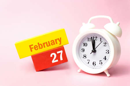 February 27th. Day 27 of month, Calendar date. White alarm clock on pastel pink background. Winter month, day of the year conceptの写真素材