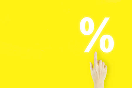 Business. Finance. Wealth. Young woman's hand pointing finger with hologram Interest rate on yellow background. Successful international financial investment conceptの写真素材