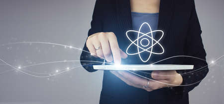 White tablet in businesswoman hand with digital hologram molecule atom on gray background