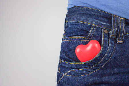 Red heart in front pocket of pants. Denim pocket with heart closeup. Relationship between people