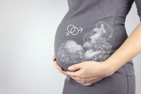 Woman standing and touching with hands her big belly with hologram fetus. Close-up, copy space.