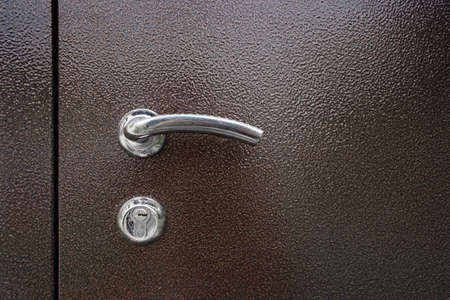 Typical Door Lock. Doorknob. A metallic keyhole with knob on a brown metal door.