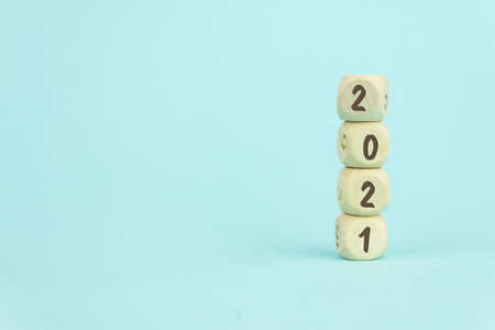 Four wooden toy cubes arranged in vertical on blue background with text 2021, business growth and management conceptの写真素材