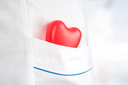 The concept of medicine and health insurance. Rubber heart in the pocket of a medical gown. Health care and patient, Failure and Diseases concept. Yearly health check up.の写真素材