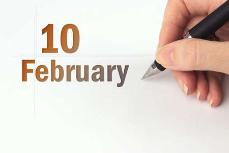 February 10th. Day 10 of month, Calendar date. The hand holds a black pen and writes the calendar date. Winter month, day of the year conceptの写真素材