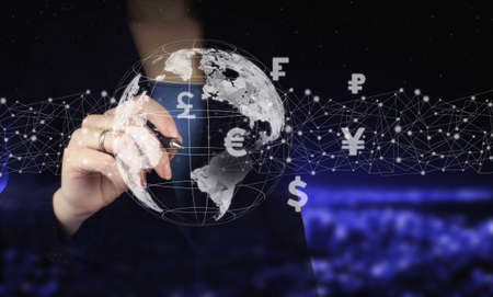 Business ideas, currency exchange, and global stock market analysis. Hand holding digital graphic pen and drawing digital hologram virtual currency, financial sign on city dark blurred backgroundの写真素材