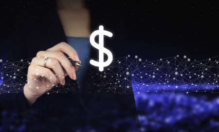 Concept of insurance or bank, currency growth. Hand holding digital graphic pen and drawing digital hologram dollar sign on city dark blurred backgroundの写真素材