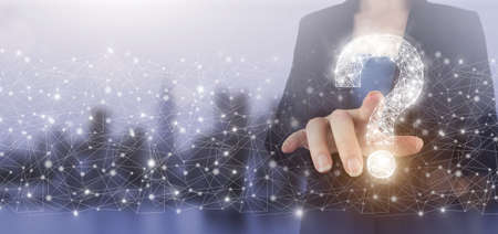 FAQ frequently asked questions concept. Hand touch digital screen hologram question mark sign on city light blurred background. Business support concept. Problems and solutionsの写真素材