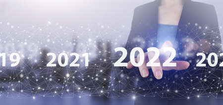 Loading year 2021 to 2022. Start concept. Hand touch digital screen hologram 2022 sign on city light...