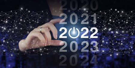 Welcome year 2022. Business new year card concept. Hand hold digital hologram 2022 sign on city dark...