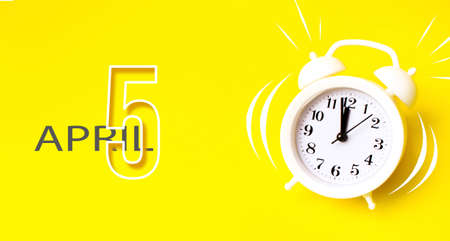April 5th. Day 5 of month, Calendar date. White alarm clock with calendar day on yellow background. Minimalistic concept of time, deadline, time to work, morning. Spring month, day of the year conceptの写真素材