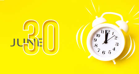 June 30th. Day 30 of month, Calendar date. White alarm clock with calendar day on yellow background. Minimalistic concept of time, deadline, time to work, morning. Summer month, day of the year conceptの写真素材
