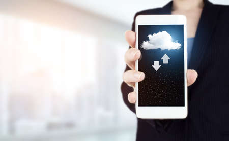 Abstract cloud technology digital. Communication network. Hand hold white smartphone with digital hologram cloud, download, data sign on light blurred back. Download Data Storage Business Technology.の写真素材