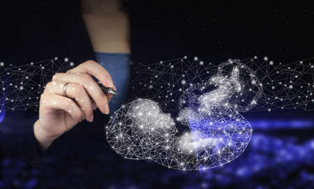 Neural networks and other concepts of modern technologies. Hand holding digital graphic pen and drawing digital hologram polygonal fetus sign on city dark blurred backgroundの写真素材