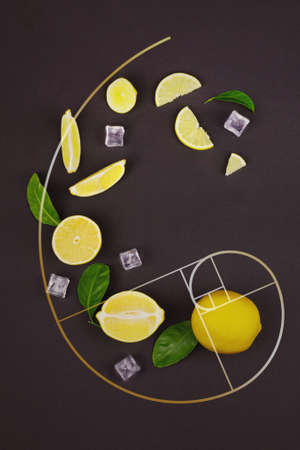 Fresh slices of yellow lemon lime fruit with green leaf and ice cube laid out on a brown background in the form of Golden Ratioの写真素材