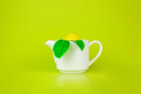 Top view of white teapot and tea leaves on green background. Refreshing Lemon Teaの写真素材