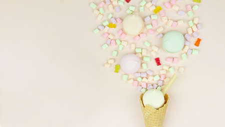 Waffle horn with colored marshmallow looks like macaroons on a pink pastel background. Holiday and celebration concept.の写真素材