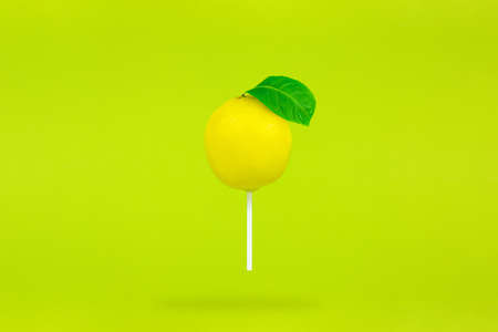 Lemon in form lollipop with stick on light green background. Single Lollipop.