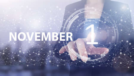 November 1st. Day 1 of month, Calendar date. Hand click luminous hologram calendar date on light blue town background. Autumn month, day of the year conceptの写真素材