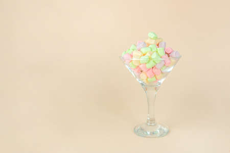 Brignt marshmallows for sweet break in wineglass on pastel beige backgroundの写真素材