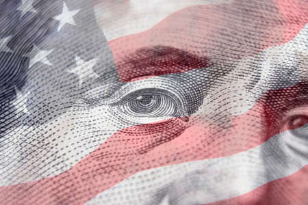 United states dollars hundred money bill. Benjamin Franklin on american flag background. Hundred dollar bill close-up fragmentの写真素材