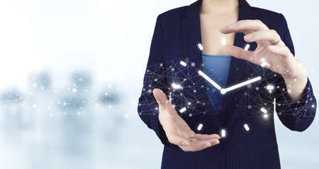 Time Timing Punctual Schedule Management Concept. Two hand holding virtual holographic clock icon with light blurred background.の写真素材
