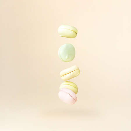 Different types of marshmallows looks like macaroons in motion falling on beige pastel backgroundの写真素材
