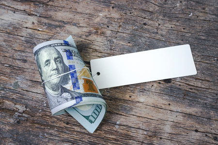 One hundred American dollars with blank white cardboard price tag or label. Twisted United States dollars, hundred USD banknotesの写真素材