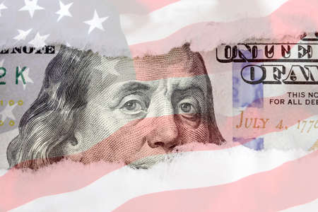 Benjamin Franklin's eyes from a fragment of new 100 dollar with american flag background. Benjamin Franklin. Hundred dollar bill close-up fragmentの写真素材
