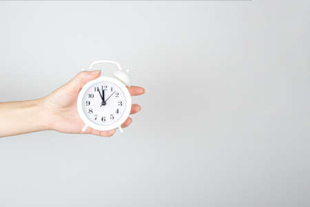 Time management, punctuality, awakening concept. Hand holding alarm clock on light backgroundの写真素材