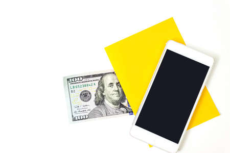 Close up blank yellow piece of paper, 100 dollar bill and empty screen mobile phone on blue backgroundの写真素材