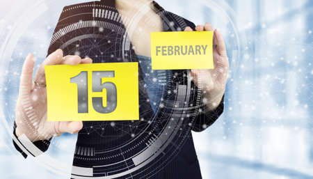 February 15th. Day 15 of month, Calendar date. Business woman hand hold yellow sheet with calendar date on blurred office background. Winter month, day of the year conceptの写真素材