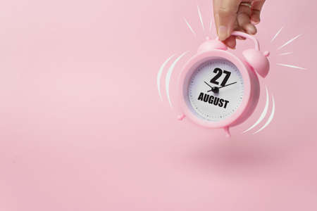 August 27th. Day 27 of month, Calendar date. The morning alarm clock jumping up from the bell with calendar date on a pink background. Summer month, day of the year conceptの写真素材