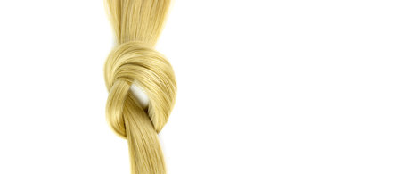 Strand of blond silky hair lock tied in knot on a white background. Hairdresser salon equipment concept, premium hairdressing setの写真素材