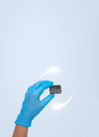 Woman hand holding x-ray of tooth with Protective vortex around on pastel blue background. Dentist stomatology medical concept. Training oral hygieneの写真素材