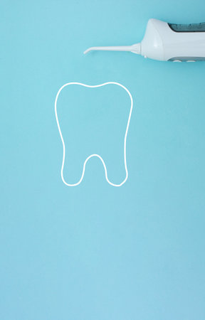 Irrigator near with tooth model silhouette on blue background, professional clean teeth, will good healthy. Dentist tools. Teeth care, dental health concept. Means to careの写真素材
