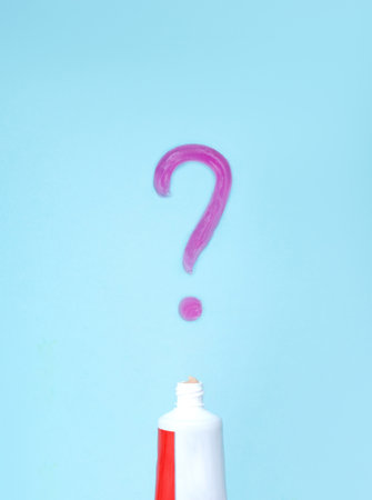 The problem of choosing toothpaste. Toothpaste and toothpaste question on blurred blue background. Oral Care Concept. Concept of oral hygiene in the familyの写真素材
