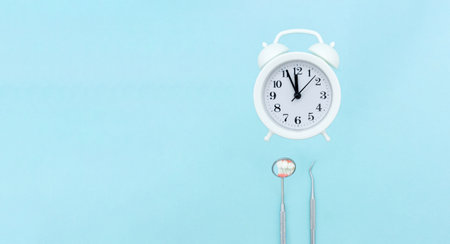 Dentist Professional tools medical equipment and white alarmclock on Blue background. Dental Hygiene...