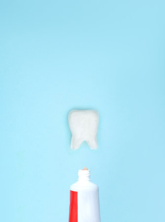 Closeup of a toothpaste and tooth model on blurred blue background. Means to care for the oral cavityの写真素材
