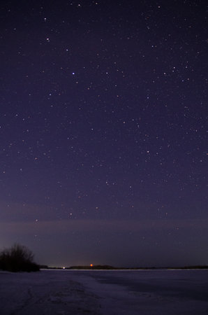 View of the starry sky over the Irtysh river covered with ice