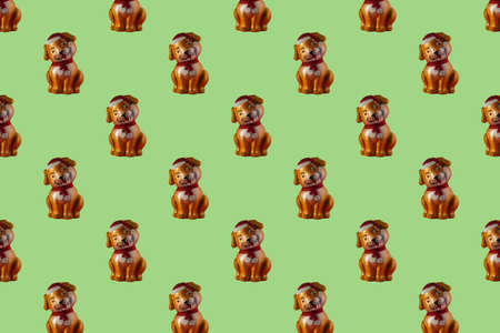 A toy dog in a red hat and with a scarf tied in the form of a seamless pattern on a green background. Christmas Seamless Pattern.の写真素材