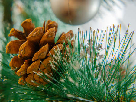 christmas composition. Close-up of a pine cone on a Christmas tree. In the background, a toy ball and a snowflake are blurred. A colorful greeting card for a Merry Christmas and a happy new year.の写真素材