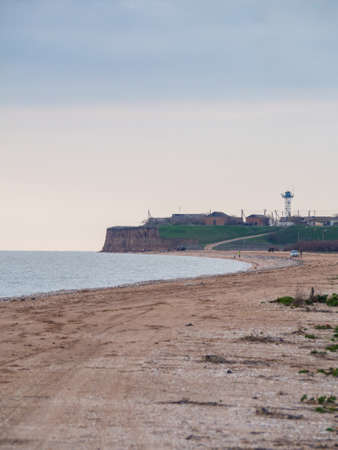 View of the sea coast in early spring. Rural seascape. Buildings on a high bank next to a sandy beach. A picture of real life. A place to relax in a quiet place.の写真素材