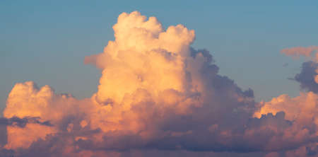 A huge white-pink volumetric cloud in the blue sky.の写真素材