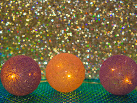 Christmas trinkets in a row on a shiny background. Christmas and New Year garland made of cotton ball on a sparkling bokeh background.の写真素材