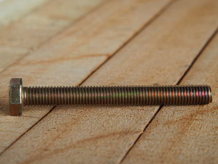 golden bolt. Chrome-plated metal bolt on wooden planks, shallow depth of field.